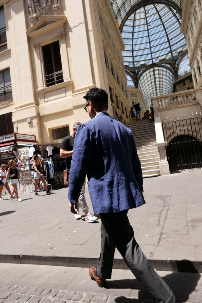 A man in a blue linen jacket walks beneath the summer light at Galleria Umberto I in Naples. The historic arcade and relaxed movement capture an everyday Neapolitan moment.
