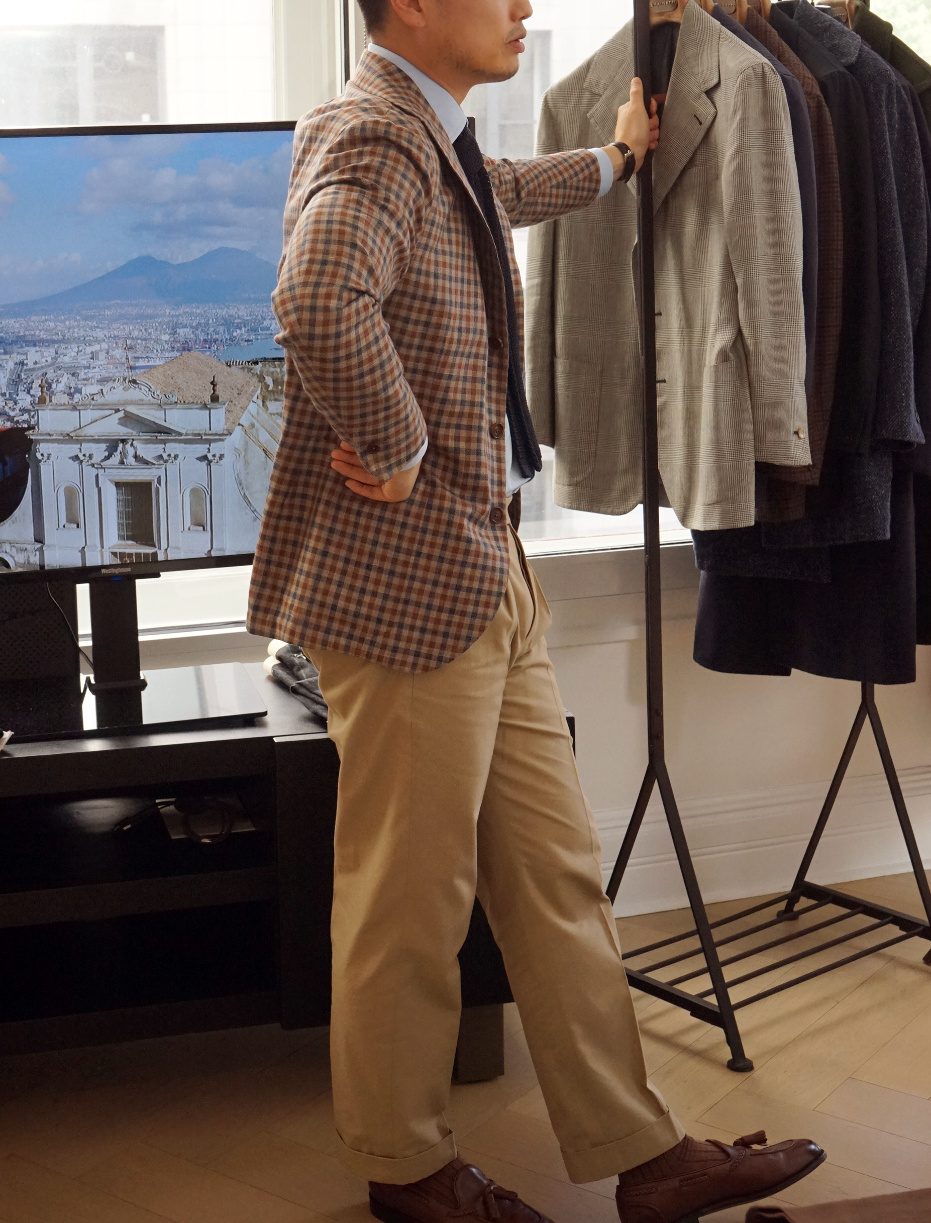 Bespoke tailor reviewing handmade jackets in a Naples atelier specializing in Neapolitan tailoring.